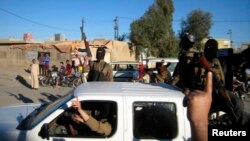 Al-Qaida fighters celebrate on vehicles taken from Iraqi security forces on a main street in Fallujah, west of Baghdad, Iraq, March 20, 2014.