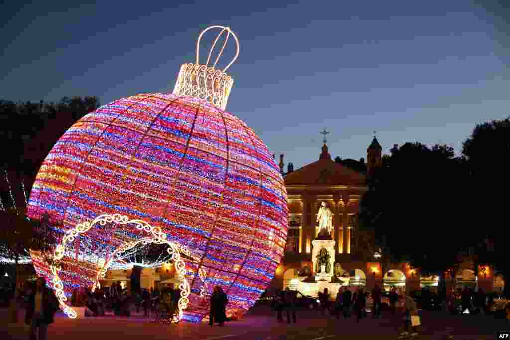People walk by a giant Christmas ball displayed in Nice, southeastern France.