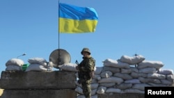 FILE - A Ukrainian serviceman stands guard at a checkpoint near the town of Armyansk in Kherson region adjacent to Crimea, March 21, 2014.