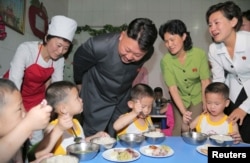 FILE - North Korean leader Kim Jong Un smiles as children eat during his visit to the Pyongyang Orphanage on International Children's Day in this undated photo, June 2, 2014.