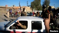 Al-Qaida fighters celebrate on vehicles taken from Iraqi security forces on a main street in Fallujah, west of Baghdad, Iraq, March 20, 2014.