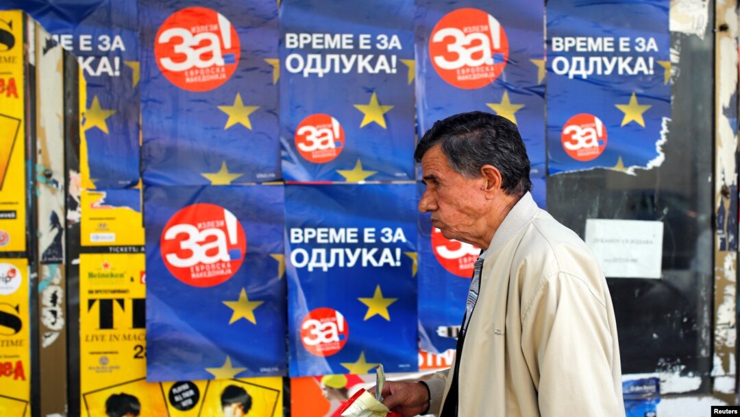 A man passes posters reading "yes" for the referendum in Macedonia on changing the country's name that would open the way for it to join NATO and the European Union, in Skopje, Macedonia, Sept. 28, 2018.