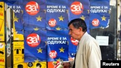 A man passes posters reading "yes" for the referendum in Macedonia on changing the country's name that would open the way for it to join NATO and the European Union, in Skopje, Macedonia, Sept. 28, 2018.