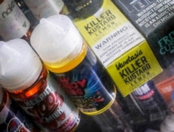 FILE- Flavored vaping solutions are shown in a window display at a vape and smoke shop in New York, Sept. 16, 2019.