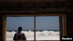 A man looks at the sea, seen through the window of a hotel that was recently abandoned after it was destroyed by a sudden rise in water level, that damaged several hotels and houses in the coastal towns east of Abidjan in August, in Grand Bassam, Ivory Coast September 20, 2023