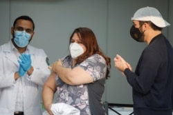 El presidente de El Salvador, Nayib Bukele (der), y el ministro de Salud, Francisco Alabí (izq), aplauden después de administrarse una dosis de la vacuna de AstraZeneca contra COVID-19 en San Salvador, El Salvador, el 17 de febrero de 2021.
