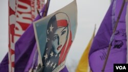 Para pemrotes membawa poster bertuliskan pesan "We the People" saat pelantikan Donald Trump sebagai Presiden ke-45 Amerika Serikat di Washington, D.C., 20 Januari 2017. (Victoria Macchi/VOA). 