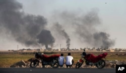 People in Akcakale Sanliurfa province, southeastern Turkey, at the border with Syria, watch smoke billowing inside Syria, during bombardment by Turkish forces, Thursday, Oct. 10, 2019