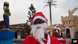 Mamadou Ngueye, who dresses as Santa Claus, waits for a guest to take a picture with at the amusement park Darkar, Senegal, Dec. 19 2015. Ngueye, is one of many Peres Noels, or Father Christmases, seen in Senegal’s capital.