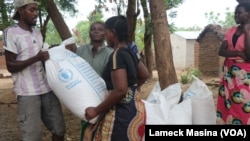 Beneficiaries of emergency food assistance in Malawi's Chikwawa district take home bags of maize provided by the United Nations' World Food Program on Oct. 2, 2024. (Lameck Masina/VOA)