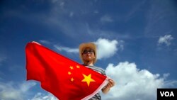 一位中国警察在在南中国海的西沙群岛上展示国旗（2014年9月14日）