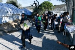 FILE - Migrants and refugees arrive at the Moria refugee camp, on the northeastern Aegean island of Lesbos, Greece, Sept. 23, 2019.