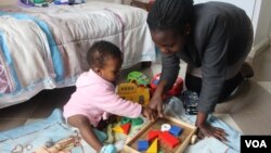 Josephine Nimile, a nanny, plays with a child at her employer's home in Nairobi, July 2015. (R. Ombuor/VOA)