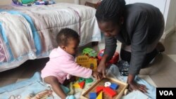 Josephine Nimile, a nanny, plays with a child at her employer's home in Nairobi, July 2015. (R. Ombuor/VOA)