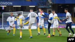 Les joueurs de Brighton portent des t-shirts de l'UEFA Champions League et de la Super League anti-européenne alors qu'ils s'échauffent avant le match de football de la Premier League anglaise entre Chelsea et Brighton et Hove Albion à Stamford Bridge à Londres le 20 avril 2021.