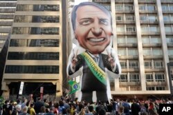 Supporters of Jair Bolsonaro, presidential candidate for the National Social Liberal Party who was stabbed during a campaign event days ago, exhibit a large, inflatable doll in his image in Sao Paulo, Brazil, Sunday, Sept. 9, 2018.