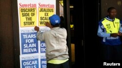 A newspaper vendor puts up posters outside the Pretoria Magistrates court where Oscar Pistorius appeared for a bail hearing, February 20, 2013.