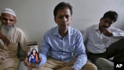 Abdul Aziz Sheikh, center, father of Sabika Sheikh, a victim of a shooting at a Texas high school, shows a picture of his daughter in Karachi, Pakistan, Saturday, May 19, 2018. (AP Photo/Fareed Khan)