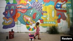A girl looks at a wall painting by Israeli artist who goes by the name Dioz, during an art happening, called POW! WOW! Israel, which is connected to a week-long art and culture festival held in Hawaii called POW! WOW! Hawaii, in the southern city of Arad,