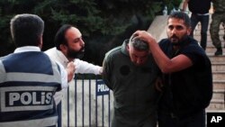 Turski građanin (drugi s leva) pljuje prema pripadniku turskih oružanih snaga kojeg privodi policijac, zbog sumnje da je umešan u pokušaj puča u julu 