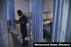 Seorang teknisi menyiapkan peralatan saat pasien berbaring di tempat tidur di ruang operasi Rumah Sakit Indonesia di Jalur Gaza utara, 4 Januari 2016. (Foto: REUTERS/Mohammed Salem)
