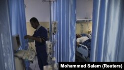 Seorang teknisi menyiapkan peralatan saat pasien berbaring di tempat tidur di ruang operasi Rumah Sakit Indonesia di Jalur Gaza utara, 4 Januari 2016. (Foto: REUTERS/Mohammed Salem)