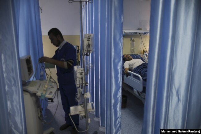 Seorang teknisi menyiapkan peralatan saat pasien berbaring di tempat tidur di ruang operasi Rumah Sakit Indonesia di Jalur Gaza utara, 4 Januari 2016. (Foto: REUTERS/Mohammed Salem)