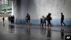 FILE - North Koreans walk along a flooded street.