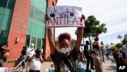 A woman holds a sign addressing antifa at a protest in Los Angeles on June 1, 2020, over the death of George Floyd, who died May 25 in Minneapolis. 