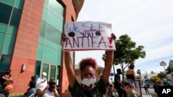 A woman holds a sign addressing antifa at a protest in Los Angeles on June 1, 2020, over the death of George Floyd, who died May 25 in Minneapolis. 