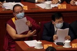 El XI Panchen Lama Bainqen Erdini Qoigyijabu (izq), quien es miembro del Comité Nacional de la Conferencia Consultiva Política del Pueblo Chino (CCPPCh), lee informe el jueves 4 de marzo de 2021.