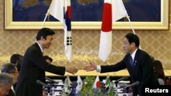 South Korea's Foreign Minister Yun Byung-se (L) reaches out to shake hands with Japan's Foreign Minister Fumio Kishida at the foreign ministry's Iikura guest house in Tokyo, June 21, 2015.