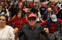 People pray together during the "Evangelicals for Trump" campaign event held at the King Jesus International Ministry as they await the arrival of President Donald Trump, Jan. 3, 2020 in Miami.