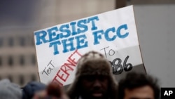 A protester holds a sign that reads "Resist the FCC. Text: INTERNET To: 52886" at the Federal Communications Commission (FCC), in Washington, Dec. 14, 2017. 