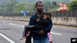 Un migrante carga a un niño por Tapachula, estado de Chiapas, México, el jueves 2 de enero de 2025, como parte de una caravana de migrantes que intentan llegar a la frontera con Estados Unidos. (AP Foto/Edgar H. Clemente).