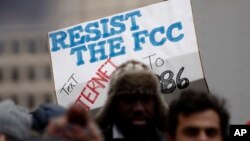 A protester holds a sign that reads "Resist the FCC. Text: INTERNET To: 52886" at the Federal Communications Commission (FCC), in Washington, Dec. 14, 2017.