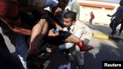 People carry a man who was injured when Libyan militiamen opened fire into a crowd of protesters in Tripoli, Nov. 15, 2013. 