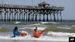 FILE - Vacationers sit in chairs along the surf in Oak Island, North Carolina, where two youths were hurt in shark attacks on June 14, 2015. 