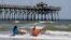 FILE - Vacationers sit in chairs along the surf in Oak Island, North Carolina, where two youths were hurt in shark attacks on June 14, 2015. 