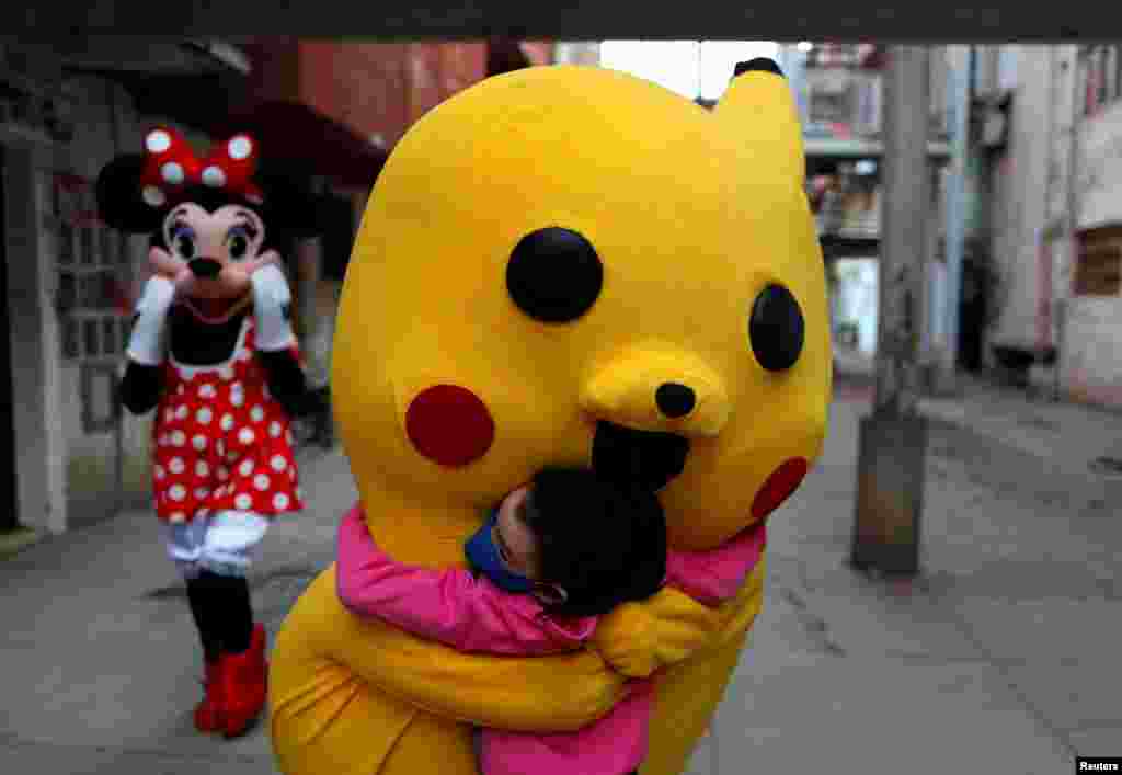 A volunteer wearing a costume of Pokemon character Pikachu hugs a child during Children&#39;s Day, in Fuerte Apache, in Buenos Aires, Argentina, Aug. 16, 2020.