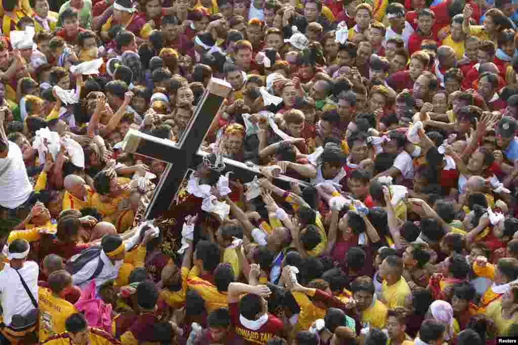 Tín đồ giành nhau cầm lấy tượng Chúa Giêsu vác thập tự giá trong một đám rước lớn tại Manila, Philippines. Bức tượng gỗ cỡ thật này, được chạm khắc ở Mexico và mang tới Philippines vào thế kỷ 17, được cho là có quyền năng chữa lành bệnh tật.