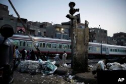 In this Oct. 23, 2018 photo, people wait for the train to pass in Shubra, Cairo, Egypt. (AP Photo/Nariman El-Mofty)