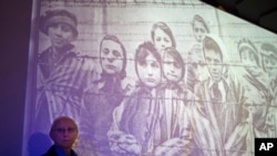 Auschwitz-Birkenau, survivant de l'Holocauste Tomy Shacham pose à côté d'une photographie qui le montre, à gauche, lors de la cérémonie de la Journée internationale du souvenir de l'Holocauste à l'Institut international Massuah pour les études sur l'holocauste au Kibboutz Tel Yitzhak, centre d'Israël, mardi 27 janvier 2015. 