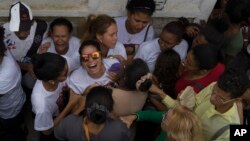 Vilma Carmo Lace, wearing sunglasses, expresses her grief during the burial of her sister Bruna Lace de Freitas, who was killed two days earlier by a stray bullet when she was inside her home, in Rio de Janeiro, Brazil, Oct. 28, 2016. 