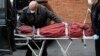 Funeral director Tom Cheeseman, left, and a colleague wear personal protective equipment due to COVID-19 concerns as they deliver a body to a funeral home, April 3, 2020, in the Brooklyn borough of New York.