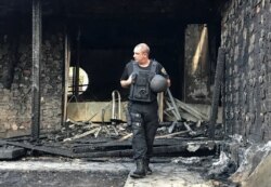 FILE - A law enforcement officer walks at the site of a burnt house, which is reportedly owned by former Governor of the Ukrainian Central Bank Valeria Gontareva, in Kyiv, Ukraine, Sept. 17, 2019.