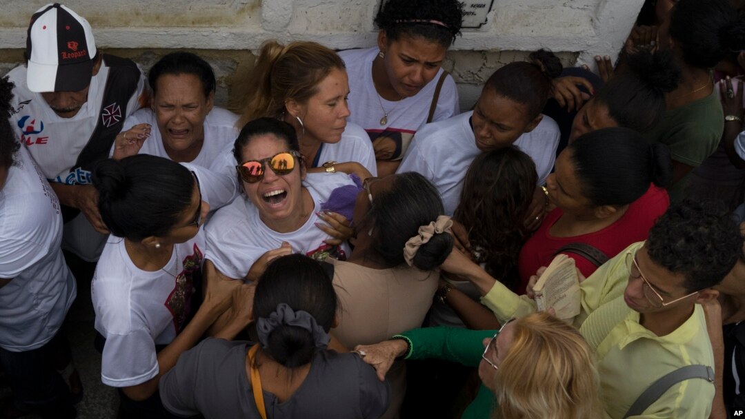 Vilma Carmo Lace, wearing sunglasses, expresses her grief during the burial of her sister Bruna Lace de Freitas, who was killed two days earlier by a stray bullet when she was inside her home, in Rio de Janeiro, Brazil, Oct. 28, 2016. 