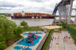 FILE - A container ship makes its the way to the Port of New York and New Jersey, passing by a playground and a skateboard park at the Bayonne Bridge in Bayonne, New Jersey, May 10, 2021.