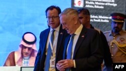 US Defense Secretary James Mattis (C) walks by as Saudi Arabia's Foreign Minister Adel al-Jubeir (L) is seen on a screen addressing the 14th International Institute for Strategic Studies (IISS) Manama Dialogue in the Bahraini capital, Oct. 27, 2018. 