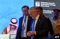 US Defense Secretary James Mattis (C) walks by as Saudi Arabia's Foreign Minister Adel al-Jubeir (L) is seen on a screen addressing the 14th International Institute for Strategic Studies (IISS) Manama Dialogue in the Bahraini capital, Oct. 27, 2018.